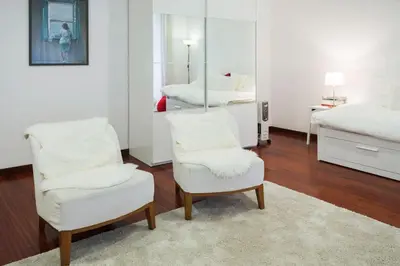 a bedroom with two white chairs and a mirror at Flores Studio in Porto