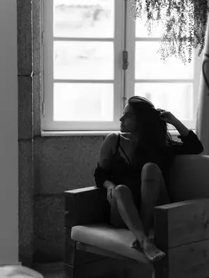 a woman sitting on a couch in front of a window at Bruval Premium Apartments - Sé Porto in Porto