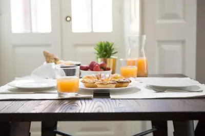 a table with a plate of food and glasses of orange juice at Gil Vicente - Charming Guesthouse in Porto