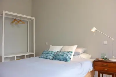 a white bed with a blue pillow on top of it at Casa Paillard, by Flat in Porto in Porto