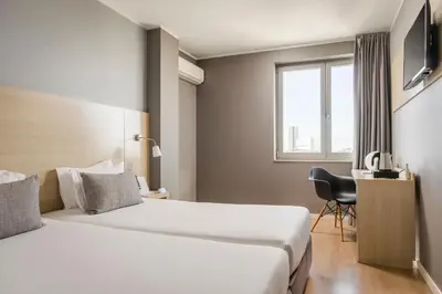 a hotel room with two beds and a chair at ClipHotel in Vila Nova de Gaia