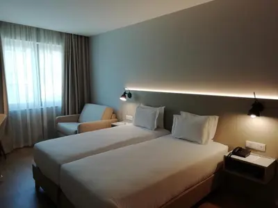a hotel room with two beds and a chair at ClipHotel in Vila Nova de Gaia