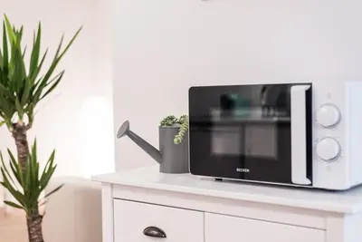 a microwave on top of a white cabinet with a plant at GuestReady - Terracota Bureau in Porto