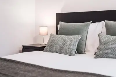 a white bed with pillows and a lamp on a table at GuestReady - Terracota Bureau in Porto
