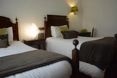 a hotel room with two beds and a lamp at Hotel Sao Jose in Porto
