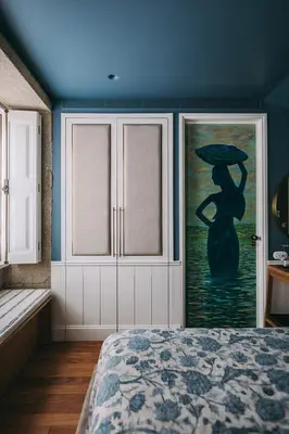 a bedroom with a painting of a woman with an umbrella at Gran Cruz House in Porto