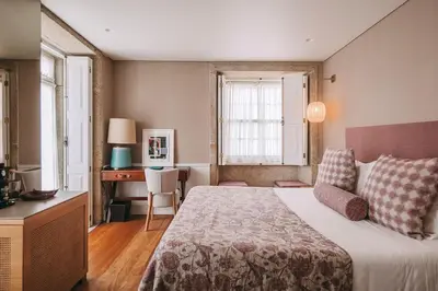 a hotel room with a bed and a desk and window at Gran Cruz House in Porto