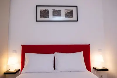 a bed with a red headboard and two lamps at Lively Getaway Apartment in Porto