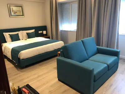 a bedroom with a bed and a couch and a chair at Vera Cruz Porto Downtown Hotel in Porto