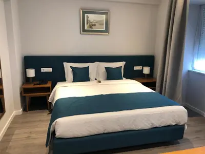 a bedroom with a large bed with blue and white sheets at Vera Cruz Porto Downtown Hotel in Porto
