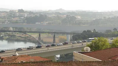 a long line of cars on a bridge over a river at Residencial Porto Novo - Alojamento Local in Porto