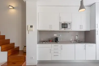 a white kitchen with a sink and a microwave at Aposentus - Arrábida Studio in Vila Nova de Gaia
