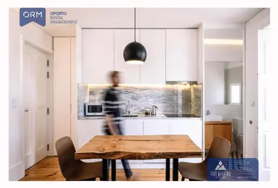 a man walking through a kitchen with a wooden table at ORM - Virtudes Apartment in Porto