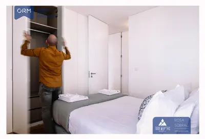 a man standing next to a bed in a bedroom at ORM - Virtudes Apartment in Porto