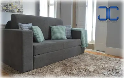a gray couch with pillows on a rug in a living room at #Four Apartment by JC in Porto