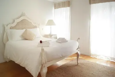 a white bedroom with a large white bed with a table at Historical Center - Taipas Apartments in Porto