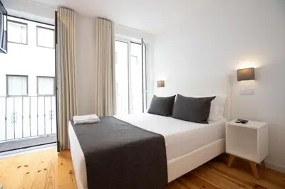a bedroom with a white bed with a large window at Mystay Porto Batalha in Porto