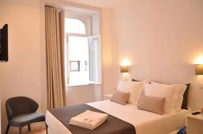 a chair and a table in a room with a window at Mystay Porto Batalha in Porto