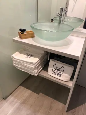 a bathroom with a sink and towels on a shelf at Porto Deluxe Suites in Porto
