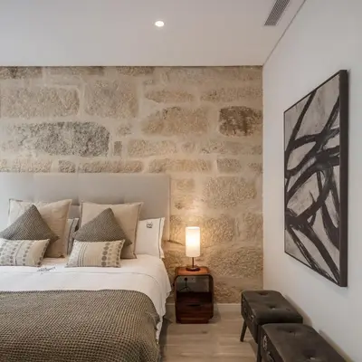 a bedroom with a bed and a stone wall at Porto Deluxe Suites in Porto