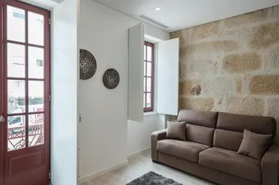 a living room with a couch and a stone wall at Porto Deluxe Suites in Porto