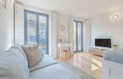 a white living room with a couch and a tv at Downtown Porto Flat, Walk to City Center in Porto