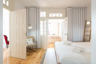 a white bedroom with two beds and a table at LovelyStay - Martires Boutique Flat in Porto
