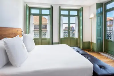 a bedroom with a white bed and two windows at One Shot Aliados Goldsmith in Porto