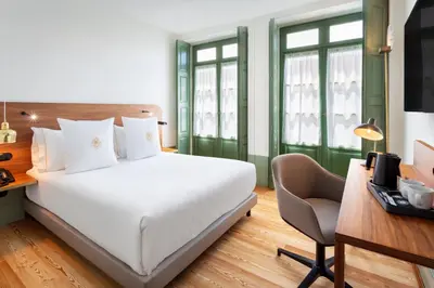 a bedroom with a bed and a desk with a chair at One Shot Aliados Goldsmith in Porto