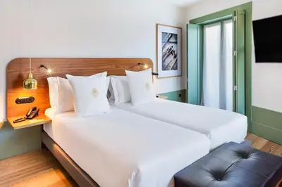 a hotel room with two beds and a chair at One Shot Aliados Goldsmith in Porto