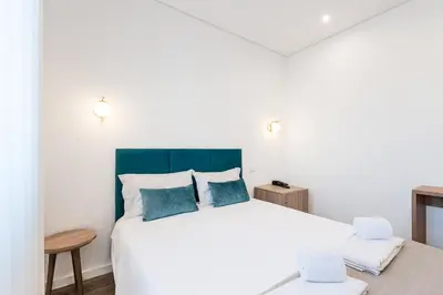 a bedroom with a large white bed with blue pillows at Hotel Grande Rio in Porto