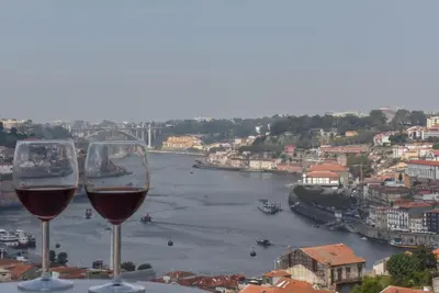 two glasses of wine sitting on a ledge overlooking a river at Porto Gaia River View 8 by MP in Vila Nova de Gaia