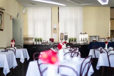 a restaurant with tables and chairs with red flowers at Hotel Universal in Porto