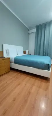 a bedroom with a bed with blue sheets and a wooden floor at Residencial Sol da Nave in Porto