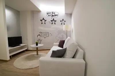 a living room with a white couch and a tv at Porto Coliseum Hotel in Porto