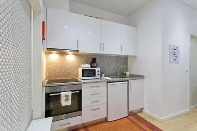 a kitchen with white cabinets and a microwave at Calm In Formosa in Porto