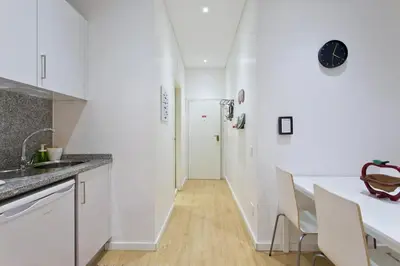 a kitchen with white walls and a counter and a hallway at Calm In Formosa in Porto