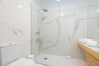 a white bathroom with a shower and a toilet at Bom Jardim Apartments in Porto