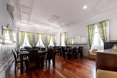 a dining room with tables and chairs and windows at Hotel do Norte in Porto