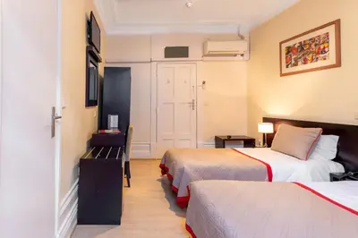 a hotel room with two beds and a door at Hotel do Norte in Porto