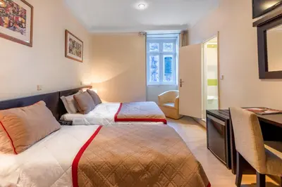 a hotel room with two beds and a desk at Hotel do Norte in Porto