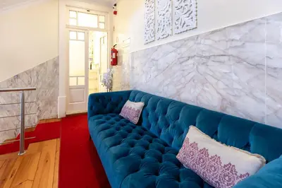 a blue couch in a living room with a marble wall at Hotel do Norte in Porto