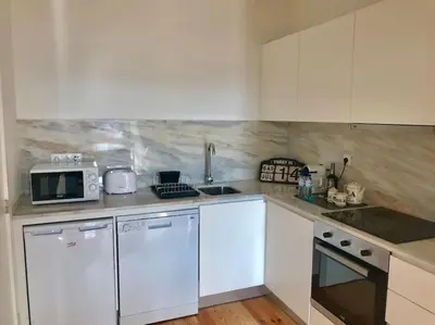 a kitchen with white cabinets and a sink and a microwave at Sé Boutique Apartment in Porto