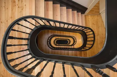 a spiral staircase with a black metal railing at HM - Ribeira São João 2D in Porto