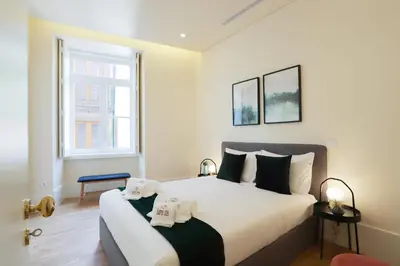 a bedroom with a large bed with two towels on it at HM - Ribeira São João 3F in Porto