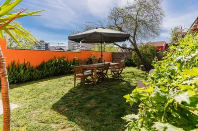a table and chairs with an umbrella in a yard at Peach Hostel & Suites in Porto