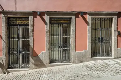 two doors on a pink building with wrought iron gates at HM - Ribeira São João 5K in Porto