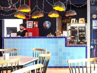 a man in a restaurant with a table and chairs at SUPERNOVA Hostel in Porto