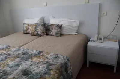 a bedroom with a bed with pillows and a phone at Hotel Peninsular- Porto in Porto