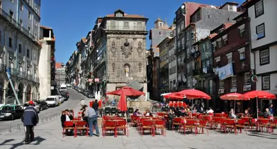 a group of tables and chairs with red umbrellas on a city street at Guest House Triunfo in Porto